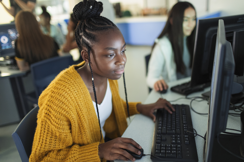 High school student typing on keyboard in computer lab.