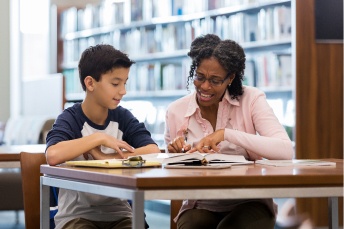 Student and teacher sitting together in a library 