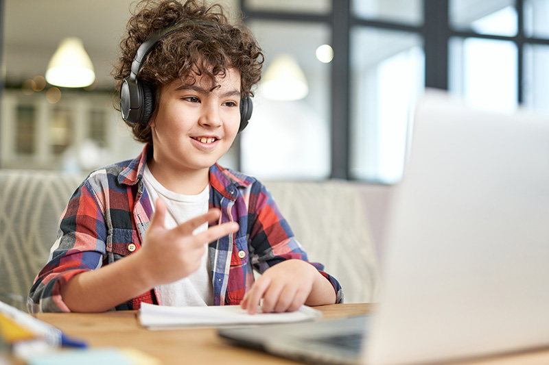 Elementary school student smiling at a laptop as he counts. 