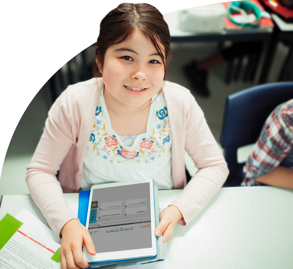 Smiling elementary student sitting at a desk while working on a tablet